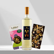Gift set featuring a bottle of light-colored wine with a gold cap, flanked by a box of gourmet chocolates and a dark chocolate bar studded with fruit and nuts